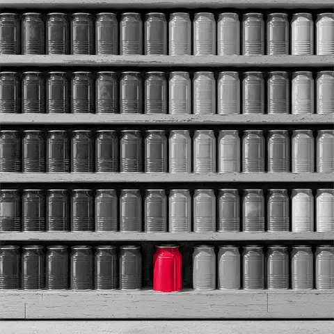 Gray cans sitting on multiple shelves with one red can on the bottom shelf in the middle