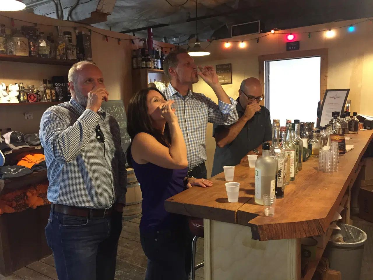 people standing around a bar sampling liquor