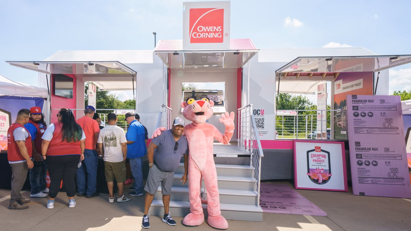 Owens Corning Insulation road show trailer sitting in a parking lot all opened up with the Pink Panther greeting people
